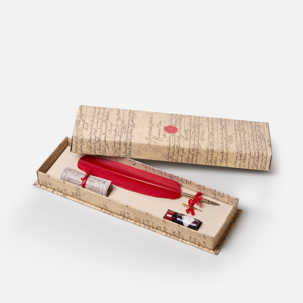 A red fountain pen set presented in an open vintage-style box with a matching closed lid. The box has a beige background printed with cursive handwriting, and the pen set includes a glossy red pen body, a small rolled letter scroll tied with red ribbon, and a small red-and-black accessory.